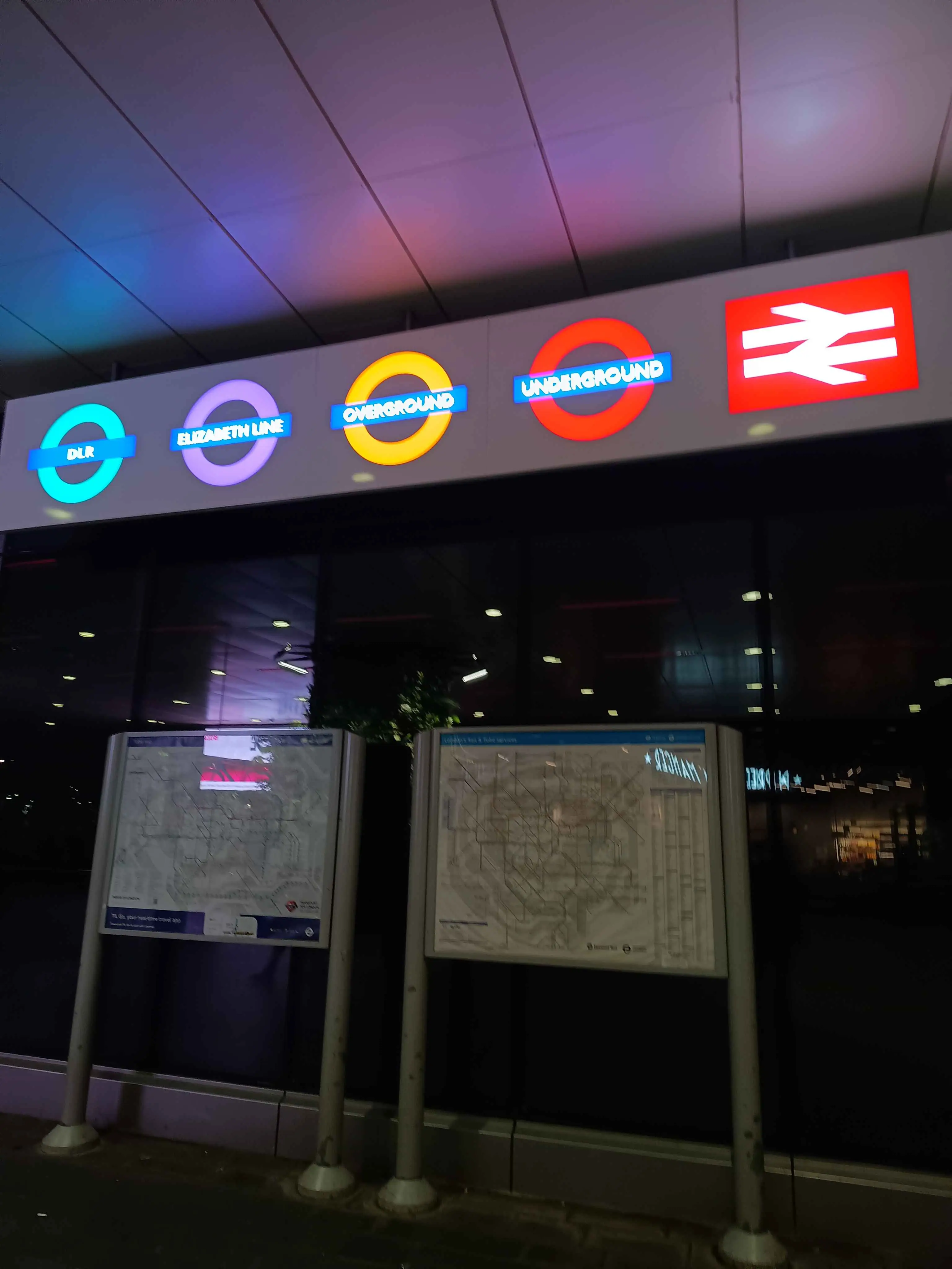 Tube map displays under a variety of colorful signs.